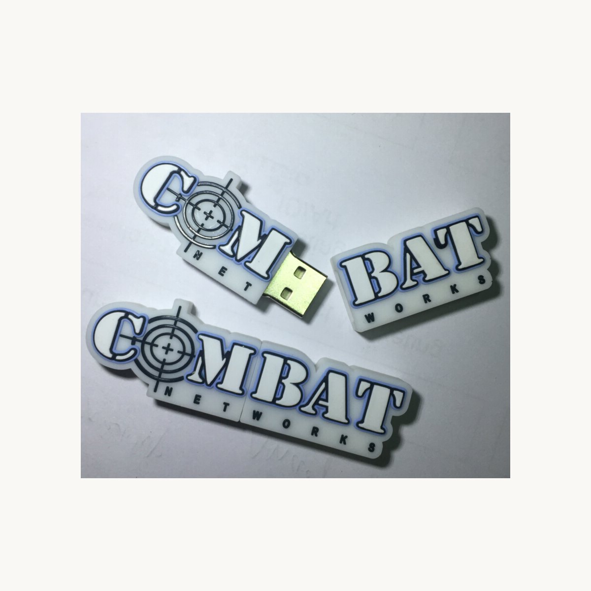 Two soft PVC moulded badge shapes photographed with a USB drive
