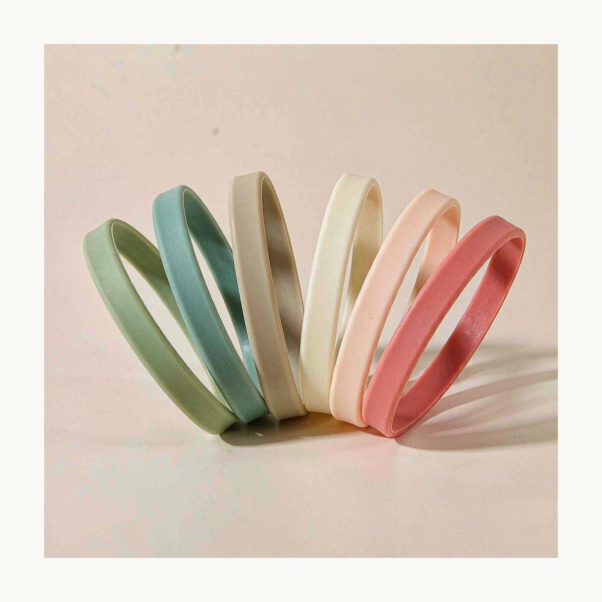Range of blank custom silicone wristbands in muted colours on an off-white background